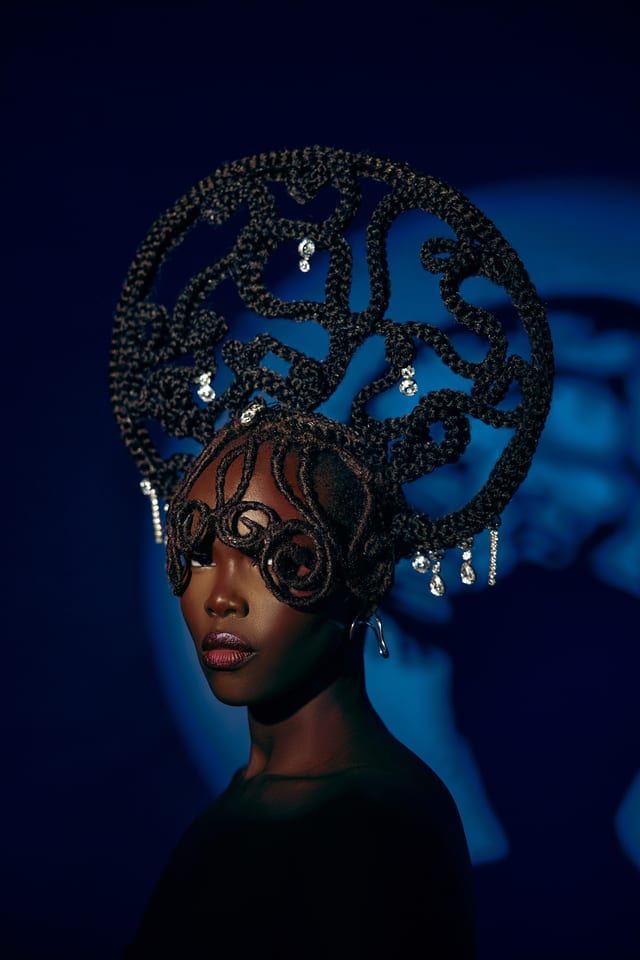 Portrait with sculptural braided headwear against midnight blue