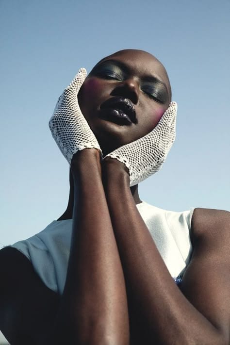 Graphic portrait with white mesh gloves against blue sky
